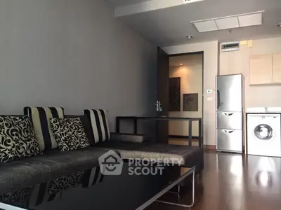 Modern living room with stylish sofa and integrated kitchen appliances in a cozy apartment.