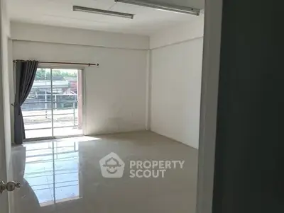 Spacious empty room with large window and tiled floor, ideal for customization.