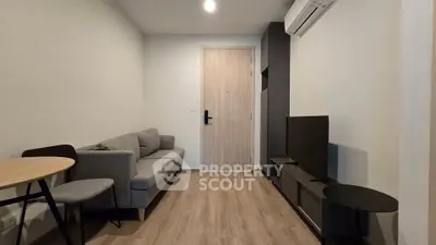 Modern living room with sleek furniture and wooden flooring, featuring a cozy sofa and flat-screen TV.