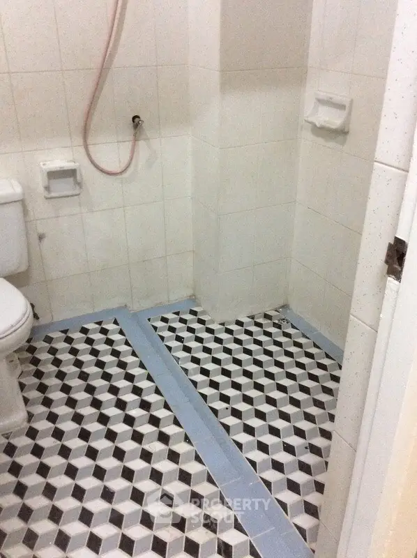 Compact bathroom with geometric tile flooring and simple white fixtures.