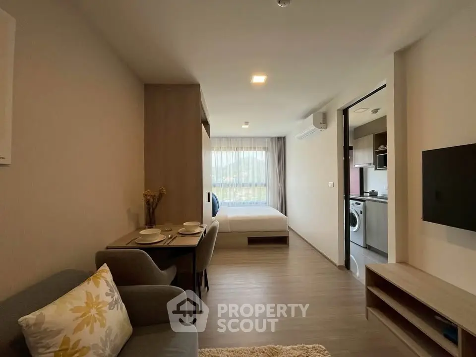 Modern studio apartment with open layout, featuring cozy living area and compact kitchen.