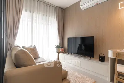 Modern living room with sleek furniture, large TV, and natural light from floor-to-ceiling windows.