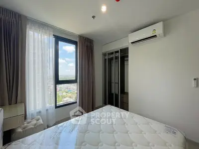 Modern bedroom with large window and city view, featuring air conditioning and closet space.