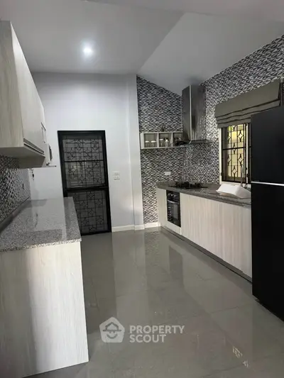 Modern kitchen with sleek cabinetry and stylish backsplash in a contemporary home.