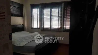 Cozy bedroom with large windows and wooden blinds, perfect for natural light lovers.