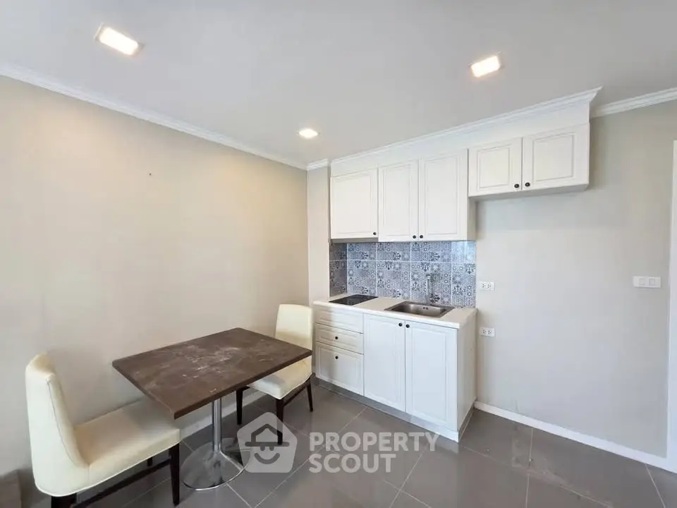 Modern kitchen with white cabinets and dining area in cozy apartment.