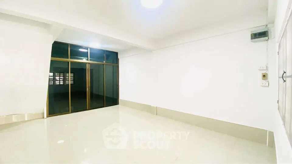 Spacious empty room with large glass doors and bright lighting, ideal for customization.