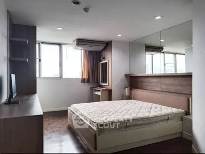 Spacious bedroom with large windows and modern furnishings in a high-rise apartment.