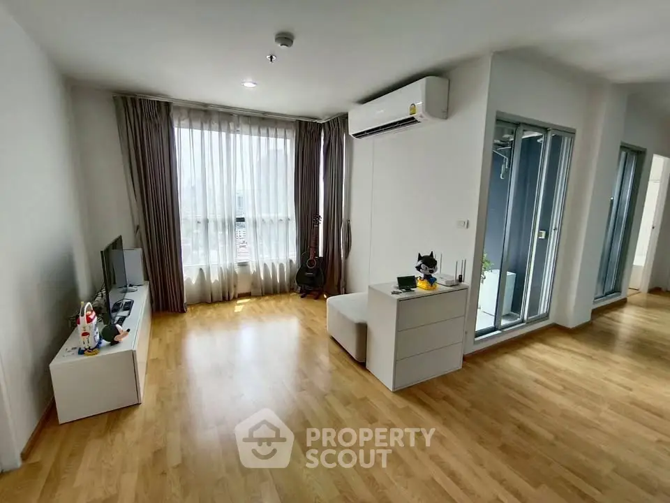Spacious modern living room with wooden flooring and large windows in a stylish apartment.