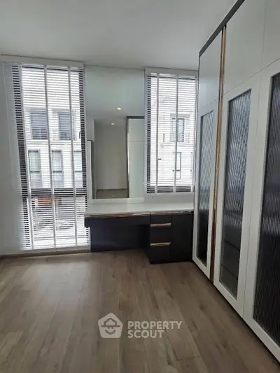 Spacious modern bedroom with large windows and built-in wardrobe in a luxury apartment.