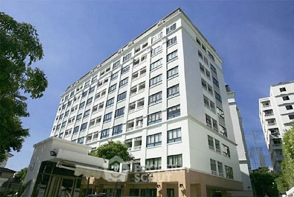 Modern high-rise apartment building with clear blue sky backdrop.