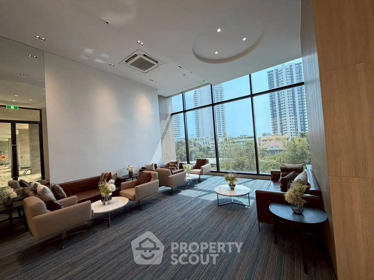 Luxurious modern lobby with floor-to-ceiling windows and elegant seating area in high-rise building.