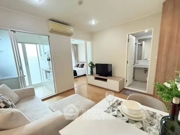 Modern living room with cozy sofa, dining area, and view into bedroom and kitchen.