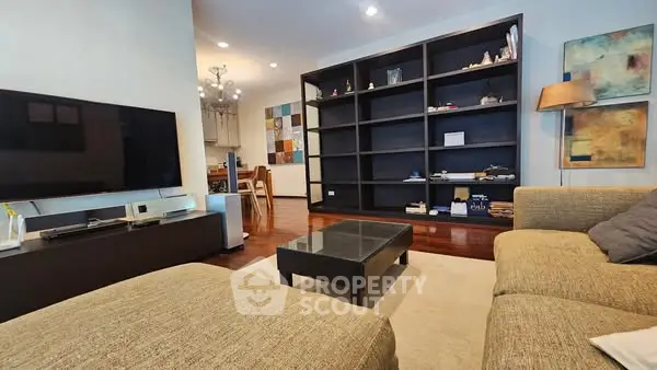 Spacious living room with modern decor and large TV, perfect for relaxation.