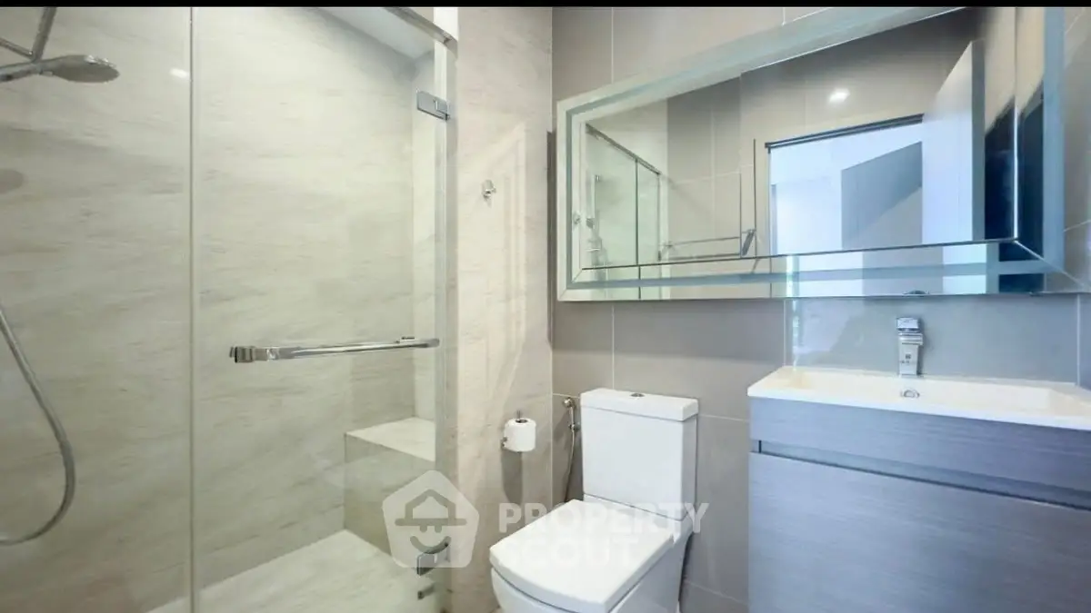 Modern bathroom with glass shower and sleek fixtures in contemporary apartment.