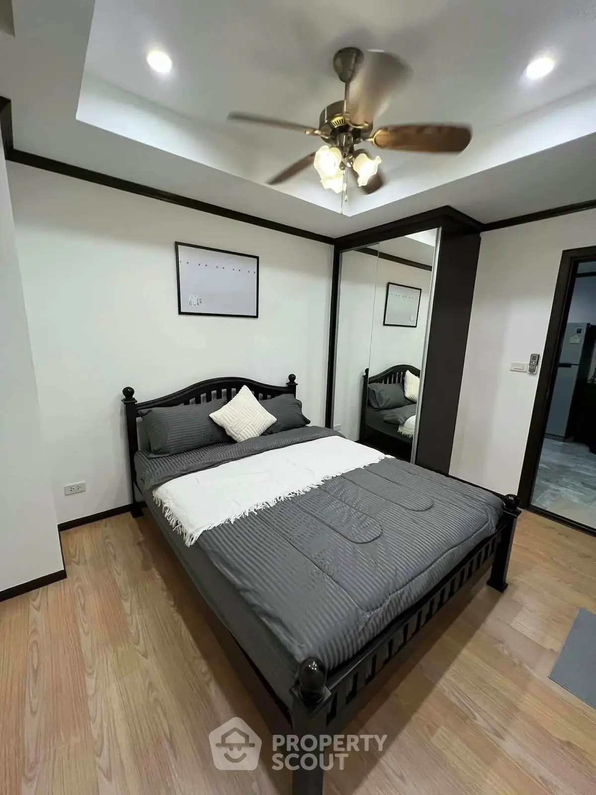Modern bedroom with stylish decor and ceiling fan in a cozy apartment.