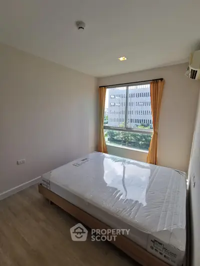 Bright bedroom with large window and modern furnishings in a contemporary apartment.