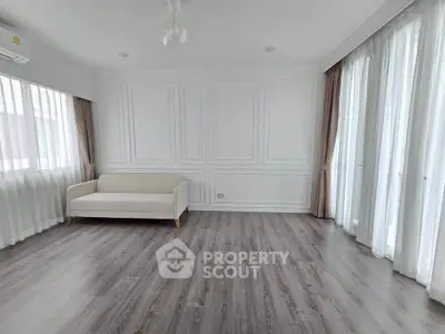 Spacious living room with elegant white panel walls and large windows for natural light.