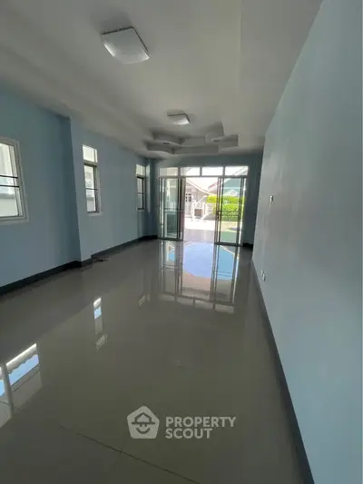 Spacious living room with large windows and glossy tiled floor