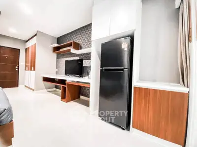 Modern apartment interior with sleek furniture and appliances, featuring a stylish TV setup and refrigerator.