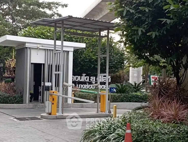 Modern gated entrance with security booth and lush landscaping