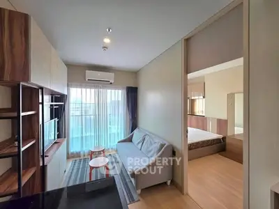 Modern apartment with open living room and bedroom layout, featuring sleek furniture and natural light.