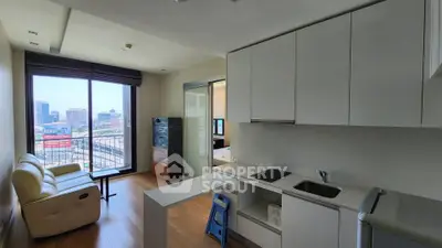 Modern apartment with open kitchen and city view from balcony, featuring sleek white cabinetry and hardwood floors.