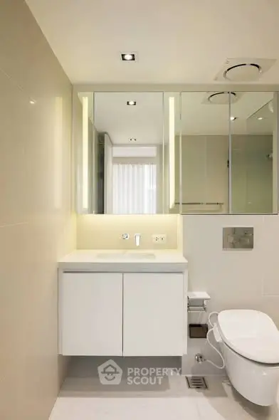 Modern bathroom with sleek design, featuring a wall-mounted toilet and illuminated mirror cabinet.