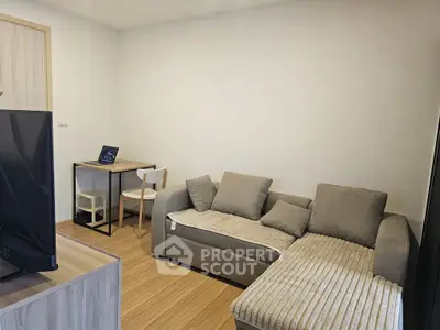 Cozy living room with modern sofa and workspace, perfect for relaxation and productivity.