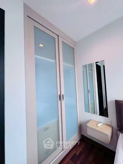 Modern bedroom with sliding wardrobe and wall-mounted mirror
