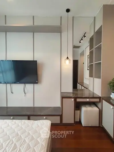 Modern bedroom with wall-mounted TV and stylish decor, featuring a cozy bed and elegant lighting.