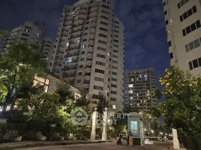 Stunning night view of modern high-rise residential buildings with lush greenery and well-lit pathways.