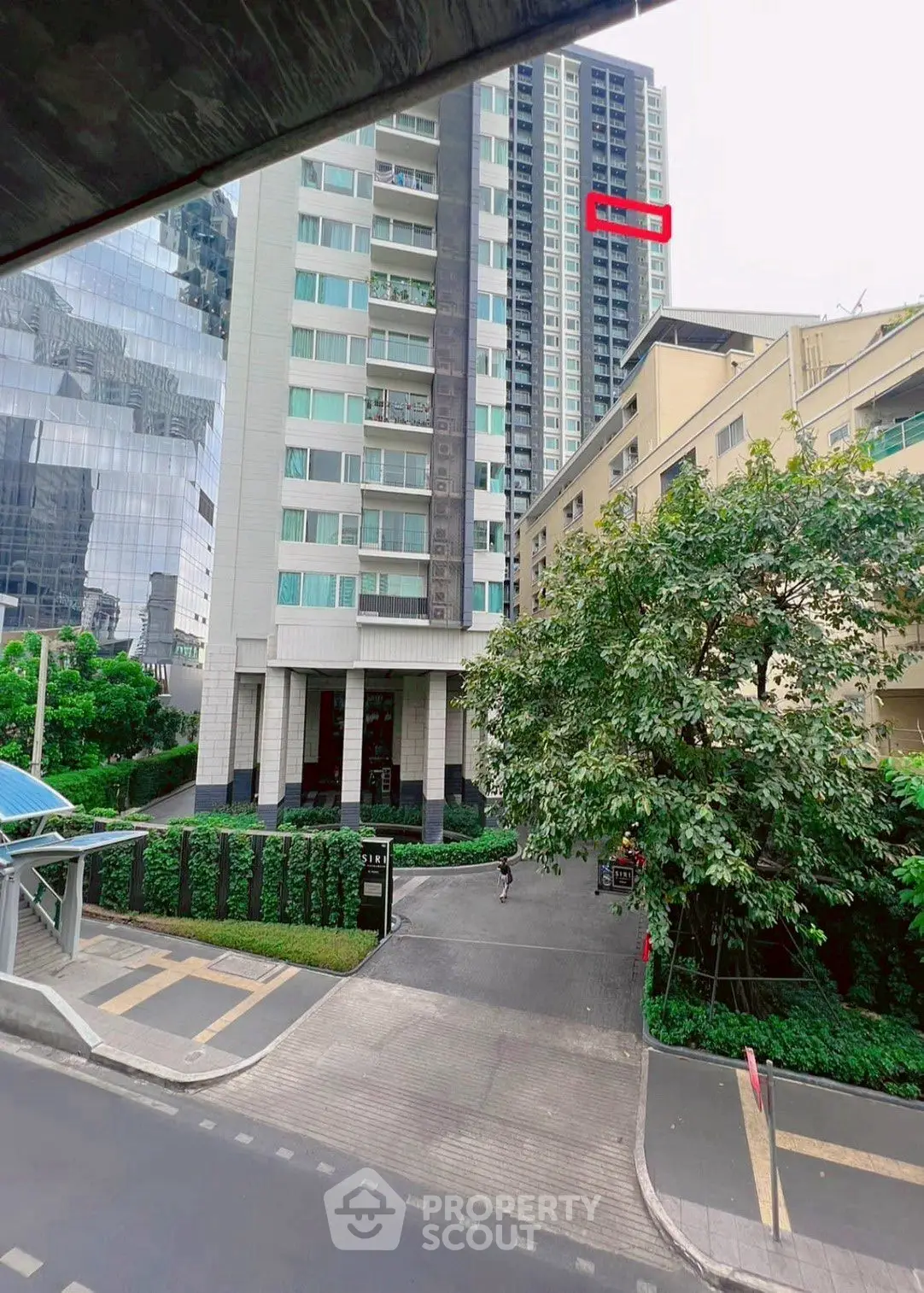 Modern high-rise building with lush greenery and urban surroundings