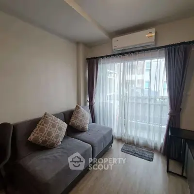 Cozy living room with modern sofa and air conditioning, featuring a balcony view.