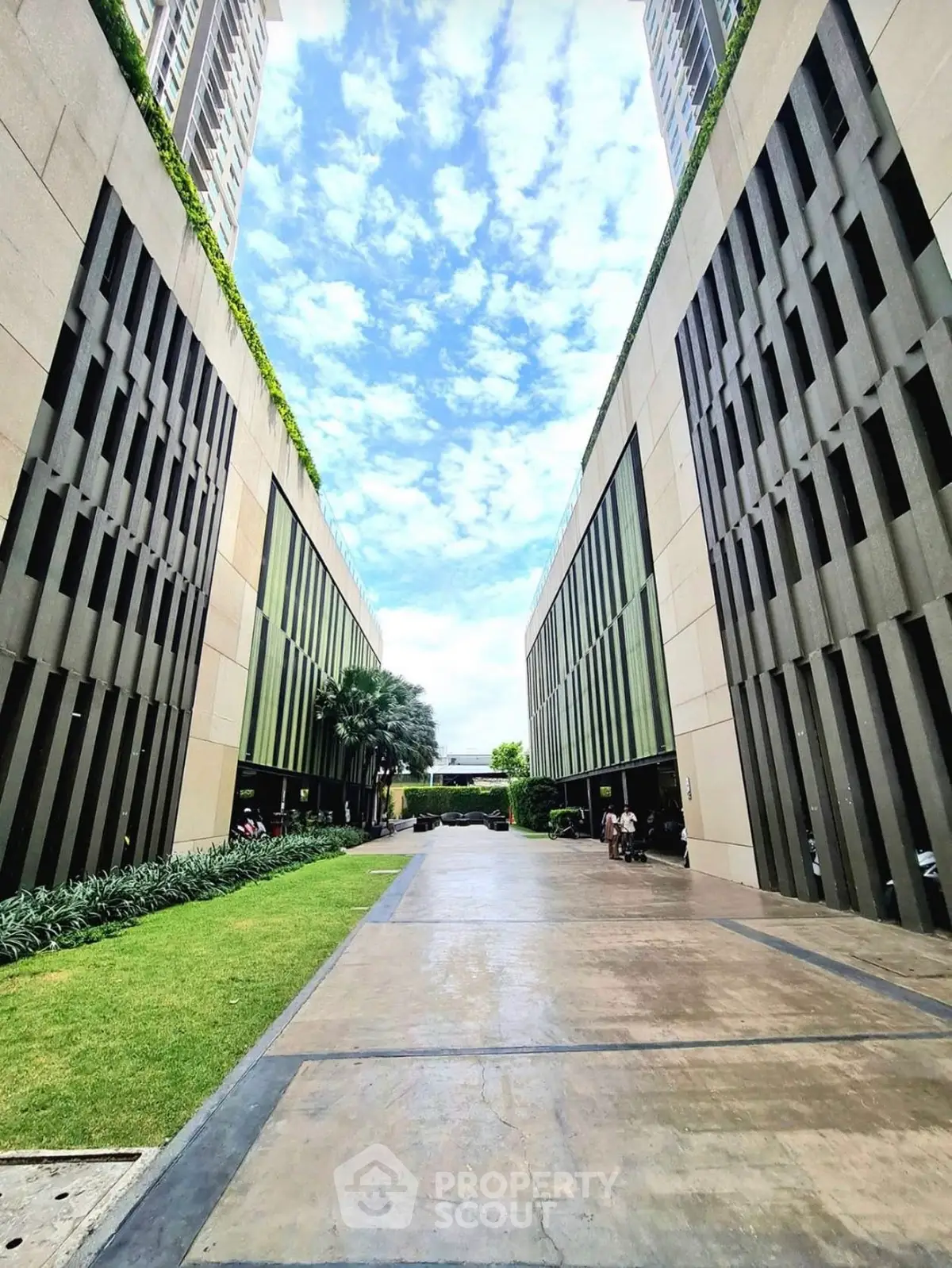 Modern building exterior with lush greenery and clear sky view