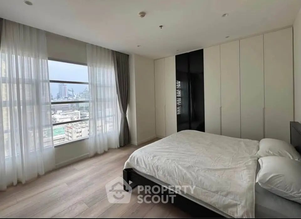 Spacious bedroom with large windows offering stunning city views, featuring modern design and ample natural light.