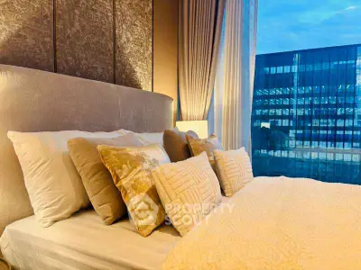 Luxurious bedroom with plush bedding and stunning city view through large window.