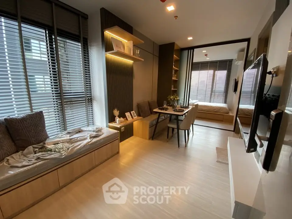Modern open-plan living room with cozy seating and dining area, featuring large windows and stylish decor.
