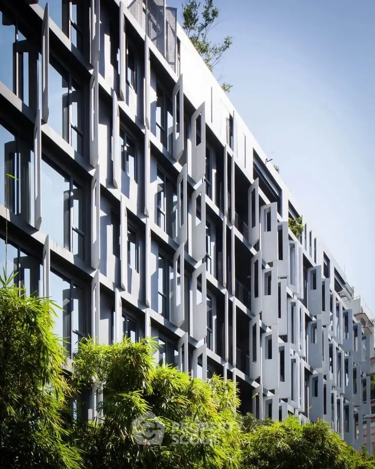 Modern architectural building facade with unique window design and lush greenery