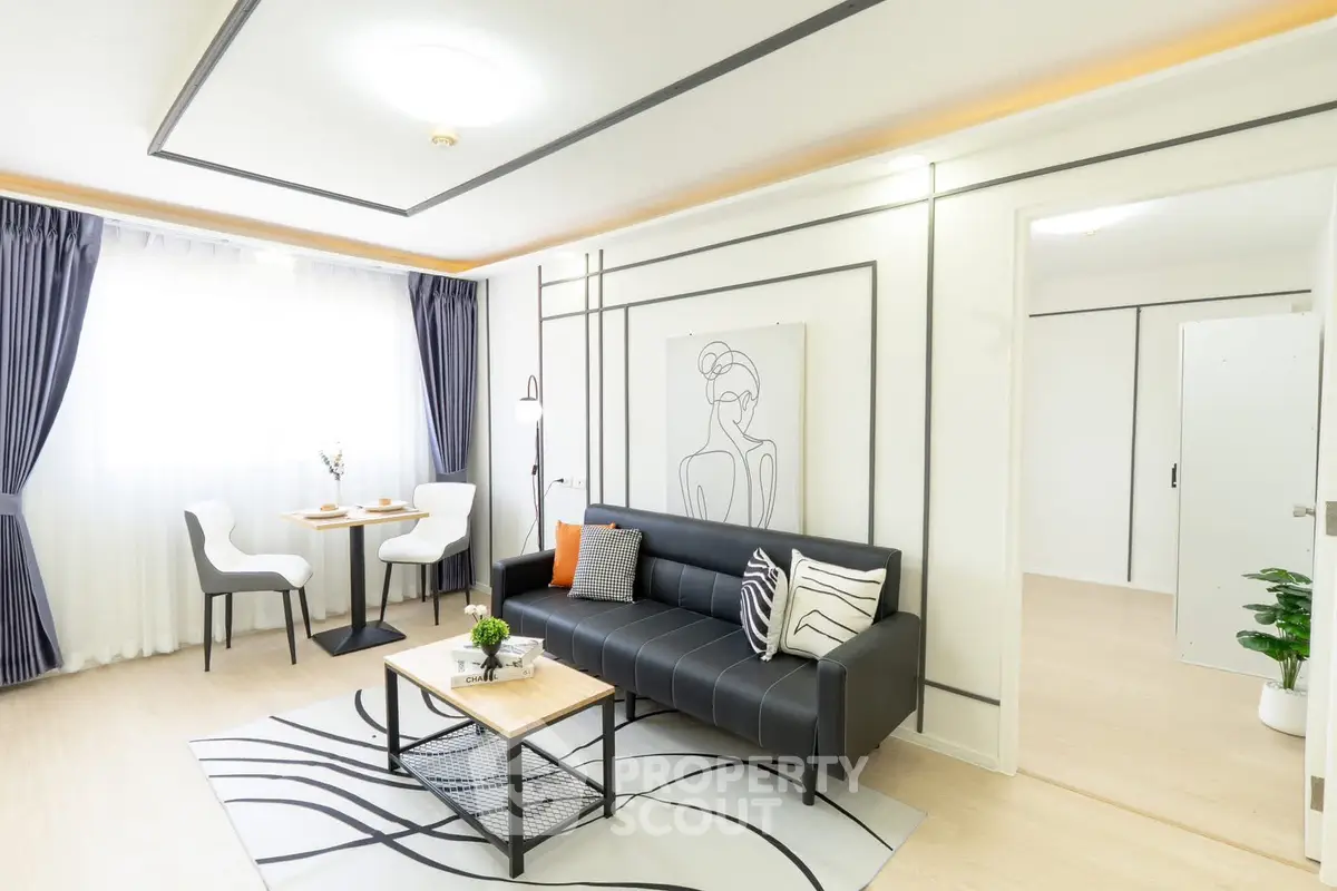 Modern living room with stylish decor, featuring a black sofa, elegant dining area, and large window with curtains.