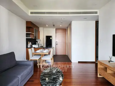 Modern open-plan living room and kitchen with sleek furniture and wooden flooring.