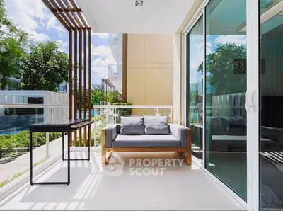 Modern balcony with stylish furniture and glass sliding doors in a contemporary apartment.