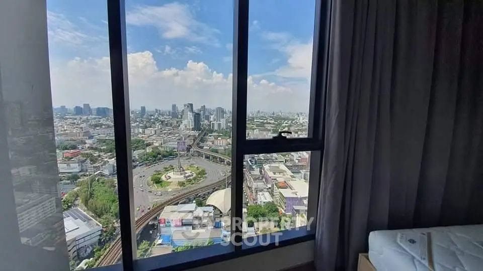 Stunning cityscape view from high-rise apartment window with clear blue sky.