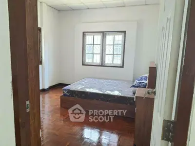 Cozy bedroom with wooden flooring and natural light from large windows.