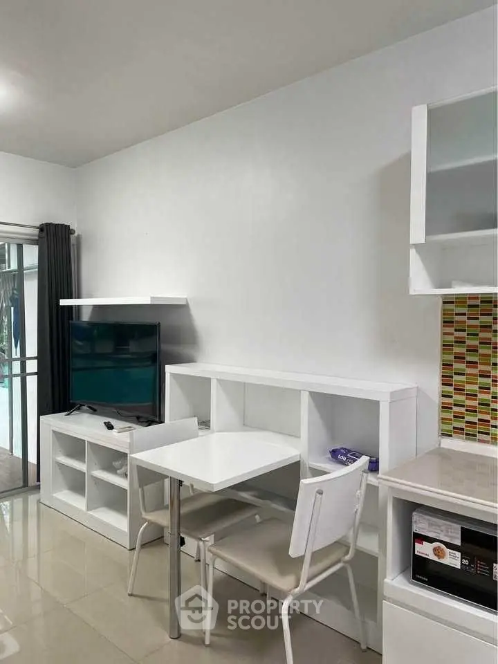 Modern living room with sleek white furniture and TV, open layout design.