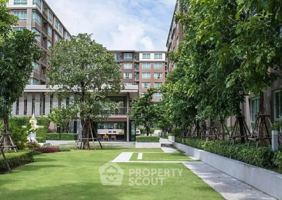 Modern apartment complex with lush green garden and contemporary architecture.