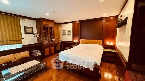 Luxurious bedroom with elegant wooden decor and cozy seating area.