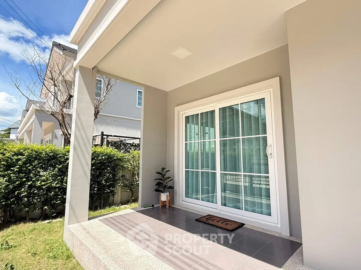 Charming modern home entrance with sliding glass doors and lush greenery, perfect for welcoming guests.