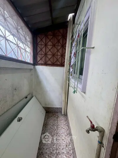 Compact utility area with tiled floor and window, ideal for storage or laundry setup.