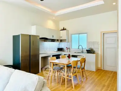 Modern kitchen with open layout, featuring sleek appliances and wooden dining set, perfect for family gatherings.